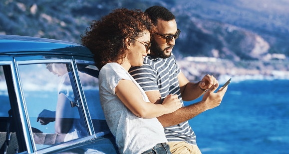 woman and man looking at smartphone on the beach